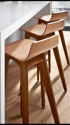 three wooden stools sitting on top of a white counter