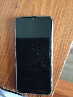 a broken cell phone sitting on top of a wooden table