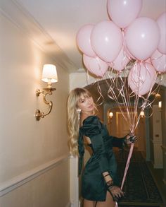 a woman holding pink balloons in her hand and posing for the camera with it's long blonde hair