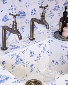 two faucets in a bathroom with blue and white wallpaper