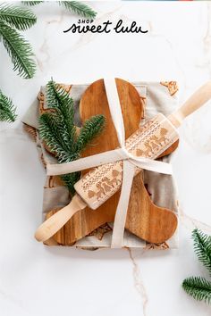 two wooden spatulas tied up on top of each other with pine branches in the background