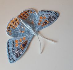 a blue butterfly with orange spots on it's wings sitting on a white surface