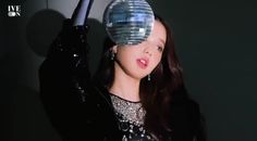 a woman holding up a disco ball in front of her face