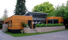 a modern house with wood siding and plants on the front