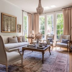 a living room filled with lots of furniture next to a window covered in drapes