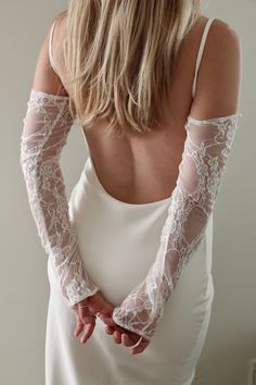 the back of a woman's white dress with lacy sleeves