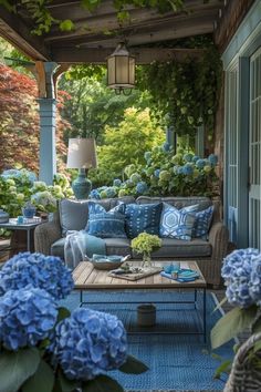 a blue couch sitting on top of a wooden floor next to a table with flowers