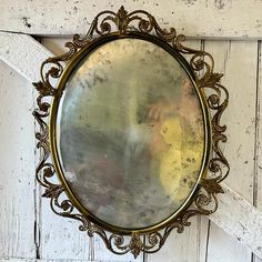 a round mirror hanging on the side of a white wooden wall next to a window