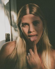 a woman sticking her tongue out and making a funny face with her hand on her lips