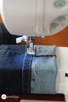 the sewing machine is on top of some blue jeans and it's stitching