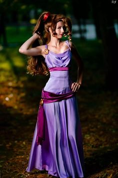 a woman with long hair wearing a purple dress and holding her hand on her head