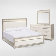 a white bed sitting next to a dresser with a mirror on it's side