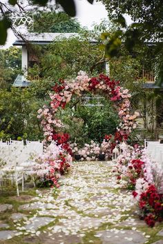 an outdoor ceremony set up with white chairs and pink flowers on the aisle, surrounded by greenery