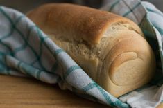 a loaf of bread sitting on top of a blue and white checkered cloth next to a wooden table