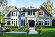 a large white house with lots of windows and bushes in front of the entrance to it