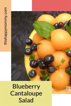 an arrangement of fruit with blueberries, oranges and mint on a black tablecloth