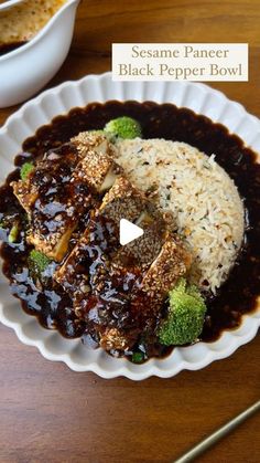 a white plate topped with rice and broccoli covered in sauce next to a bowl