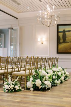 rows of chairs with flowers on them in front of a painting and chandelier