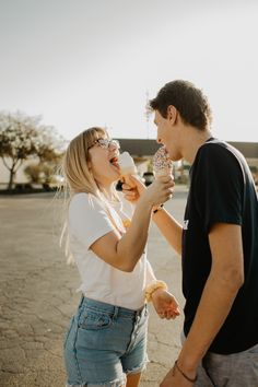 a man and woman eating donuts in the middle of an empty parking lot with no one around them