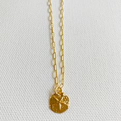 A sand dollar coin dangles from a delicate gold chain. The chain measures approximately 17 inches long is adjustable up to an inch shorter. Everyday Coin Necklace With Delicate Chain, Everyday Delicate Chain Coin Necklace, Gold Adjustable Round Disc Charm Necklaces, Adjustable Yellow Gold Charm Necklace With Coin Pendant, Everyday Round Disc Coin Necklace With Adjustable Chain, Everyday Coin Necklace With Adjustable Chain, Gold Round Pendant Necklace For Beach, Adjustable Yellow Gold Coin Necklace, Everyday Medallion Coin Necklace With Delicate Chain