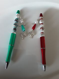 two pens are sitting next to each other on a white plate with beads and charms