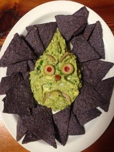 a white plate topped with chips and guacamole covered in an evil face