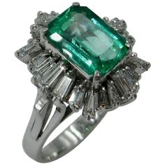 This is a stunning cocktail ring with a 2.1 Carat Emerald Cut Emerald of great beauty surrounded by 24 brilliant white Tapered Baguette Cut Diamonds totaling 1.2 Carat all set in Platinum. The jewels are of superb quality. The halo effect of the sparkling white diamonds surrounding the radiant green emerald in platinum creates a magnificent ring. And how we love the Emerald and Diamond combination! It radiates impeccable taste as evidenced by the legendary arbiter of style Jackie Kennedy who had Emerald Cocktail Ring, Emerald Cocktail, Edwardian Diamond Ring, Antique Cocktail Ring, Vintage Ballerina, Emerald Ring Vintage, Emerald Rings, Wedding Info, Platinum Diamond Rings