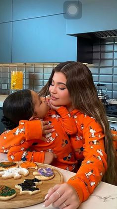 a woman kissing her son on the cheek in front of cookies