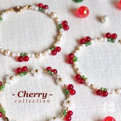 several bracelets with beads and charms on a tablecloth that says cherry collection in red, white, green and gold