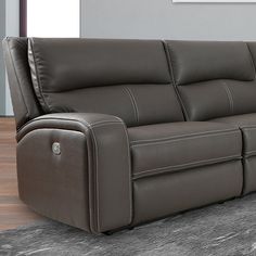 a gray leather couch sitting on top of a carpeted floor next to a wall