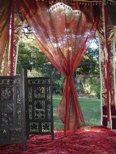 an outdoor area with red carpet, curtains and wooden doors in the middle of it