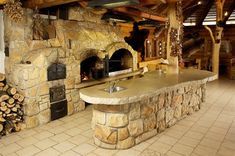 an outdoor kitchen with stone ovens and wood logs