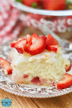 a piece of cake with strawberries on top is sitting on a plate next to a bowl of strawberries