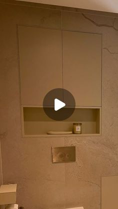 a white toilet sitting in a bathroom next to a wall mounted cabinet with a mirror above it