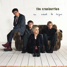 the cranberries sitting on a couch in front of a white wall with words