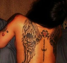 a woman laying on top of a bed with tattoos on her back and arms behind her head