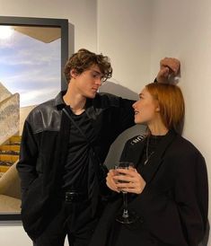 two people standing next to each other in front of a painting