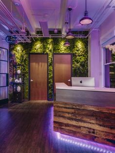 an office with wooden floors and purple lighting on the walls is lit up by lights