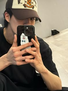 a person taking a selfie in front of a mirror wearing a hat and holding a cell phone