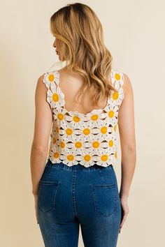 a woman wearing jeans and a crochet top with sunflowers on it