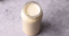 a glass bottle filled with milk sitting on top of a counter next to a spoon