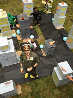 a man is standing in front of some cardboard buildings with carrots on the ground