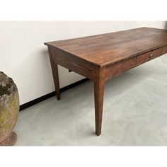 a wooden table sitting next to a potted plant on top of a cement floor