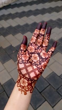 a woman's hand with henna on it and some bricks in the background