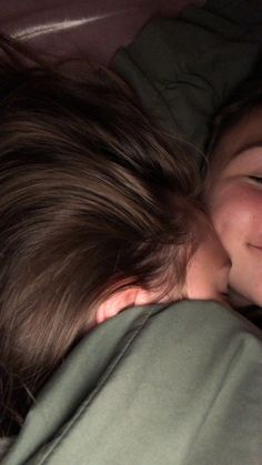 a young boy laying in bed with his head on the back of a woman's shoulder