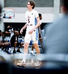 a young man standing on top of a basketball court next to a group of people