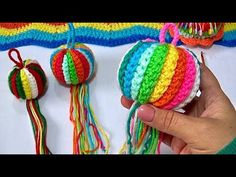 someone is holding some colorful crocheted balls with tassels on top of them