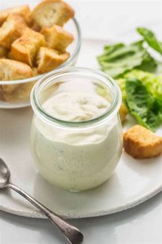 a white plate topped with food next to a bowl filled with salad and breadsticks