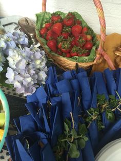 strawberries and other fruits are in baskets on the table with blue paper napkins