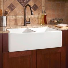 a kitchen sink sitting under a faucet next to a counter top with utensils on it